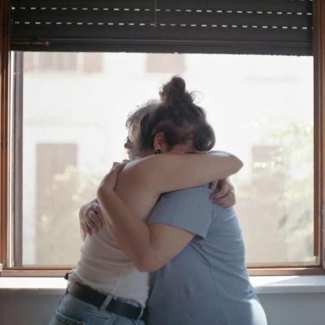 Due persone abbracciate davanti a una finestra luminosa.