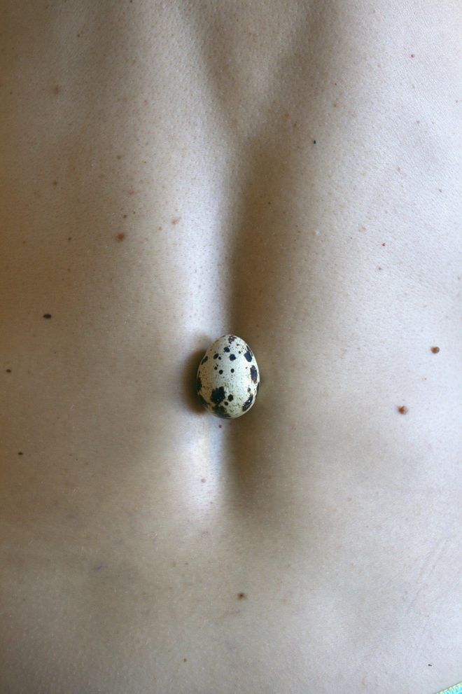Un uovo di quaglia nell'incavo della schiena, sulla pelle punteggiata di nei.